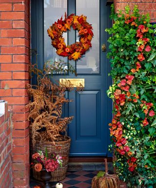 A fall wreath made of autumn colored leaves hanging on a front door