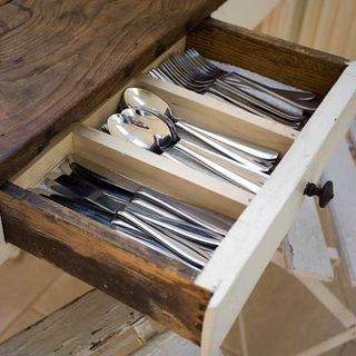 cutlery drawer with spoons knives and forks on dining table