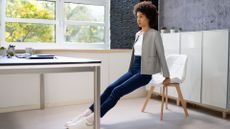 woman in work attire does tricep dips at her desk