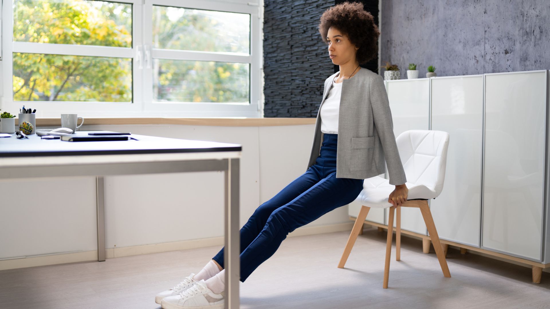 woman in work attire does tricep dips at her desk