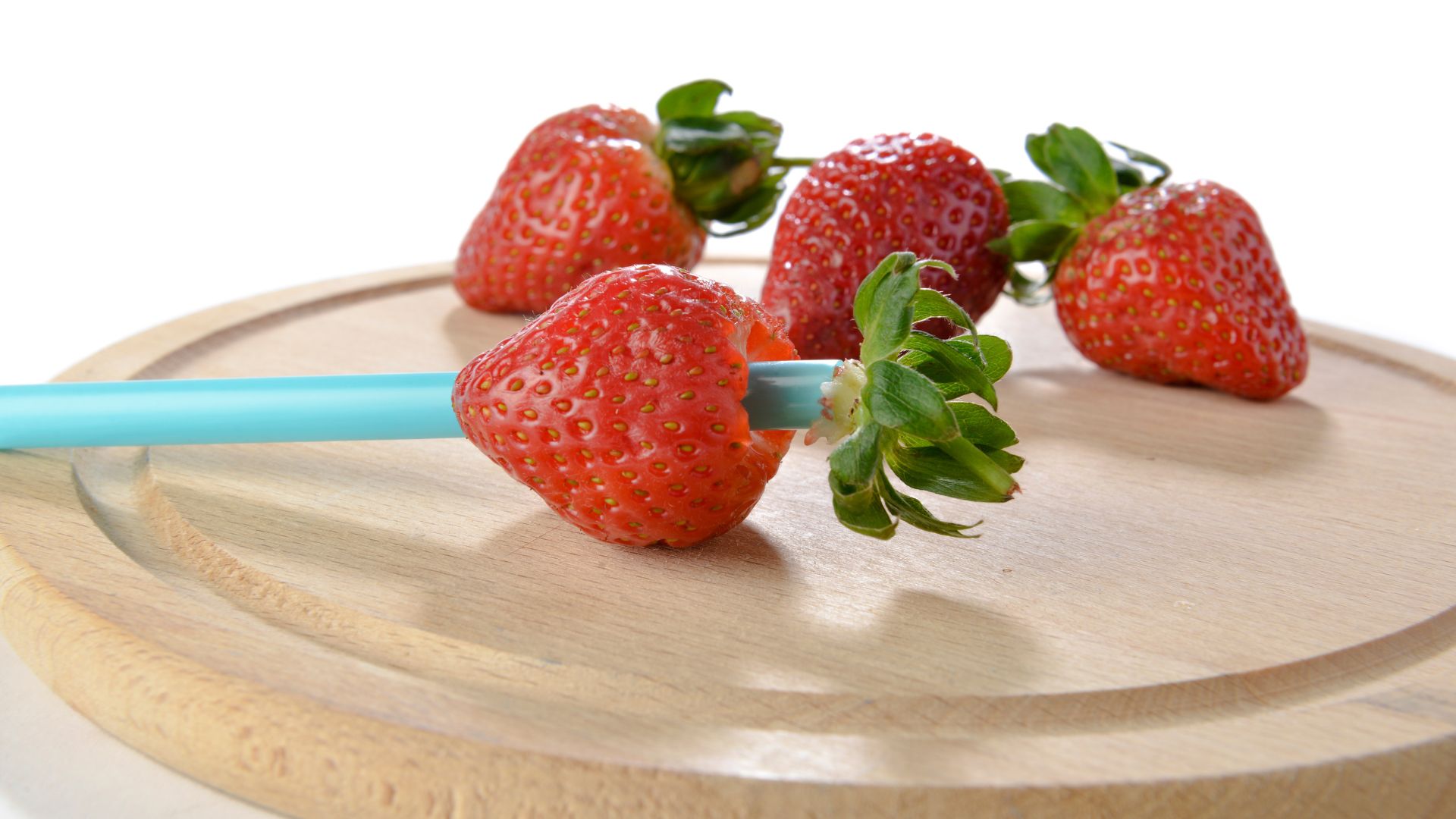 Strawberries being hulled by a straw