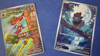 Two cards on a blue surface show a red ape hanging from a branch on a treehouse, alongside a fox-like creature walking across a branch under a full moon