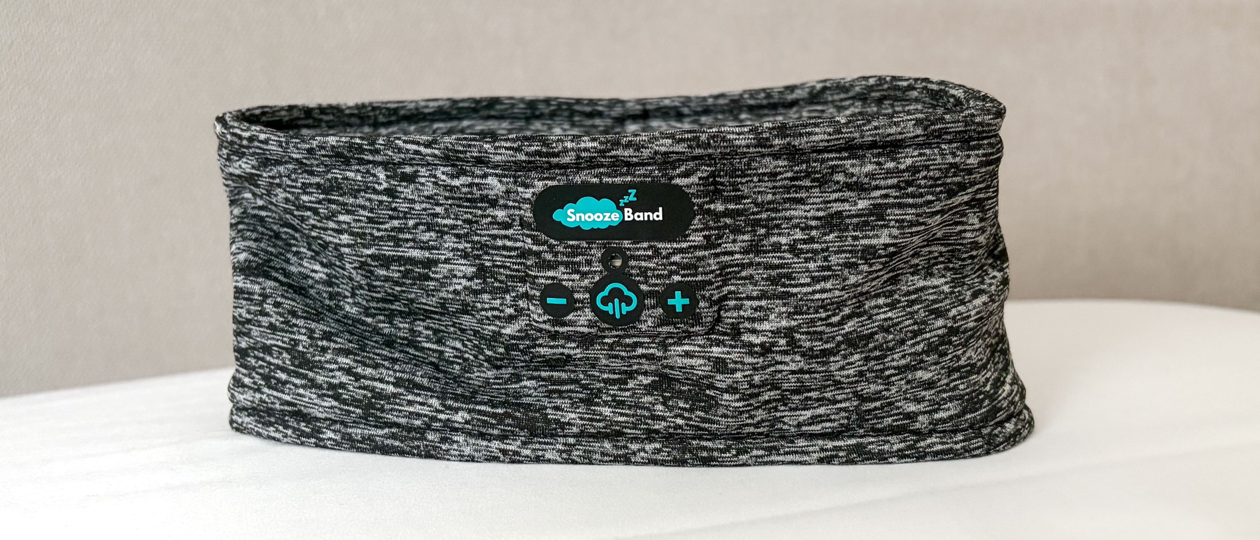 The SnoozeBand Original Bluetooth Sleep Headband balanced upright on a pillow in our reviewer's bedroom