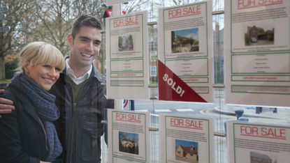 Couple looking at property listings in agency branch window