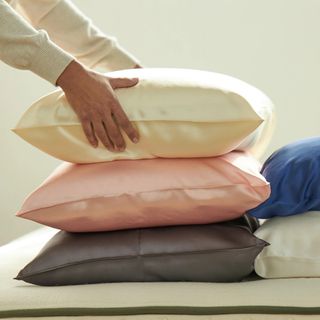 Three silk pillowcases against a beige background.
