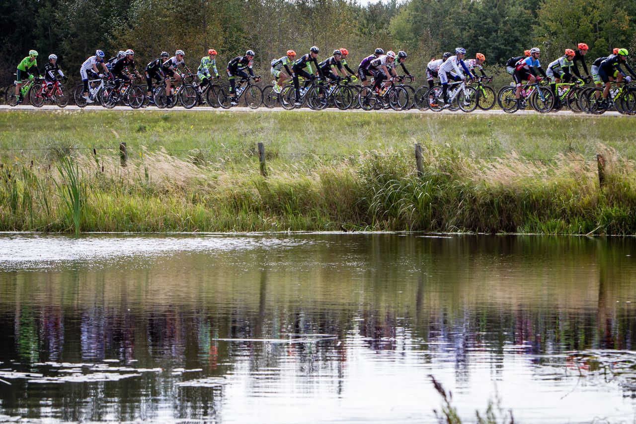 The peloton passes by a lake on stage 3 at the Tour of Alberta