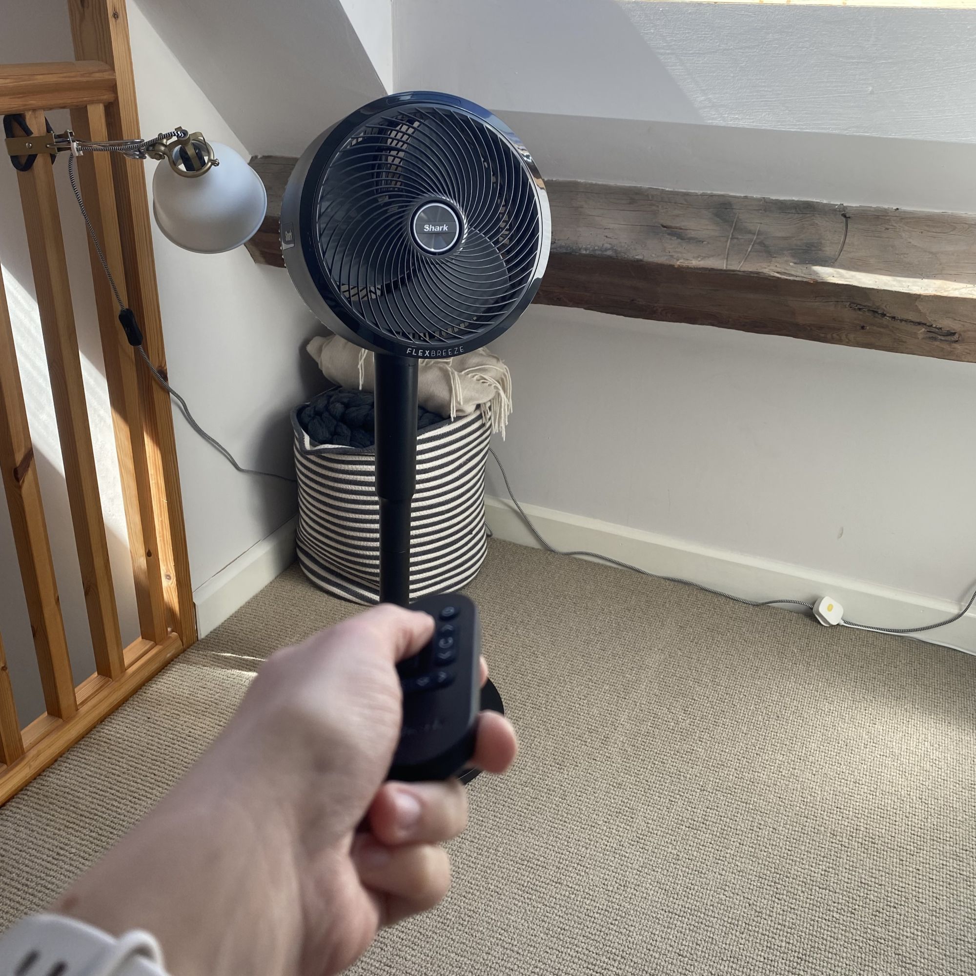 Hand using remote for Shark Flexbreeze FA220UK Fan in a loft bedroom