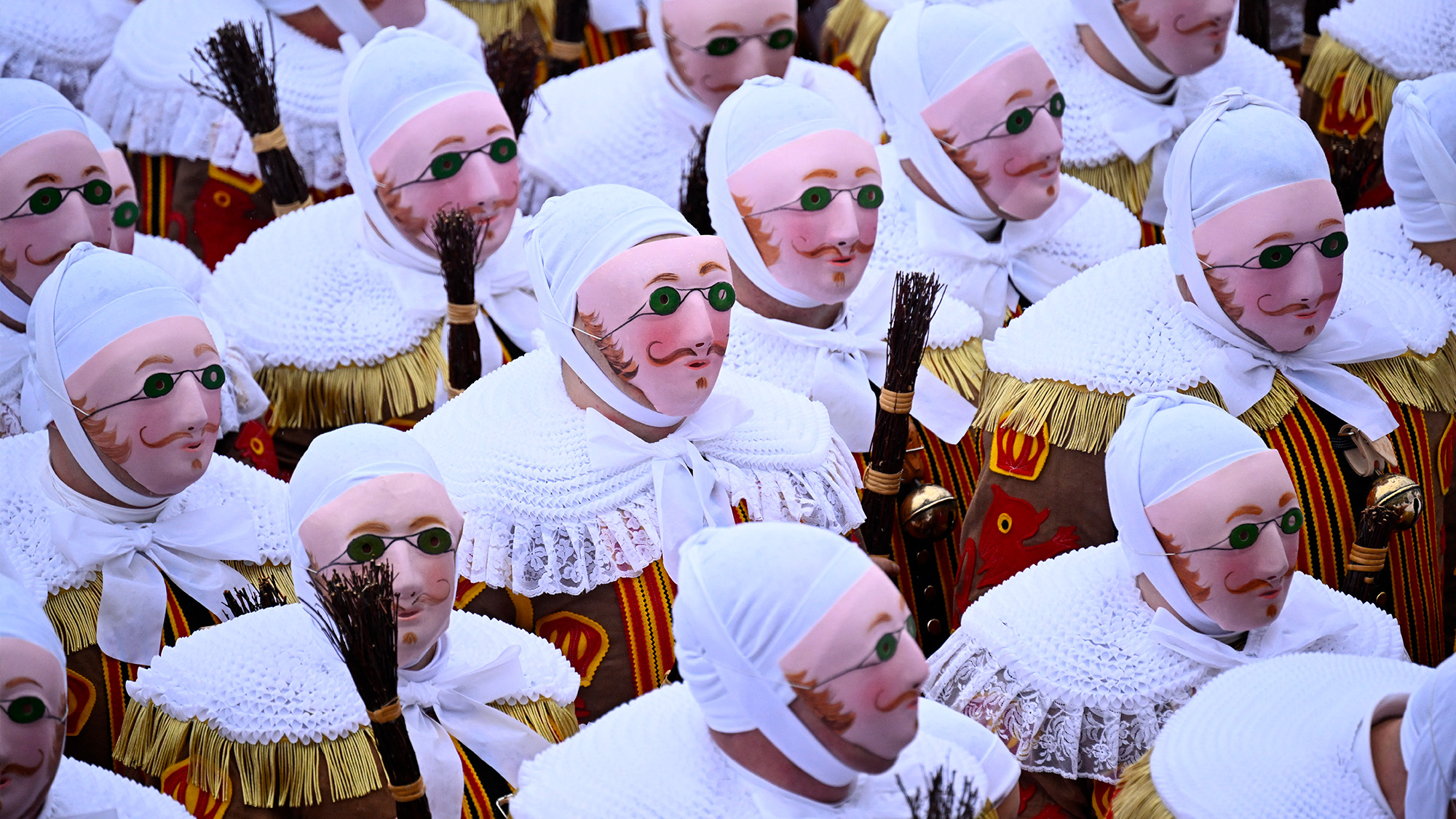 Carnival goers wear traditional wax masks and carry bundles of twigs on Shrove Tuesday parade in Binche, Belgium