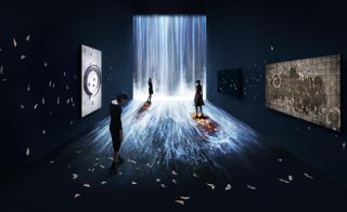 Art installation of TeamLab in the Pace Gallery. The room is dark. On the farthest wall, neon lights make out a waterfall, that cascades down the fall and onto the floor, towards us. Butterflies fly around on the walls and the floor. Three women are walking around the room.