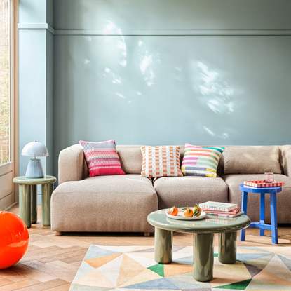 Habitat Geometric Patch Wool Cut Pile Rug in a sky blue lving room. There is an XL Calliban light in orange, beige sofa and green lacquered coffee table.