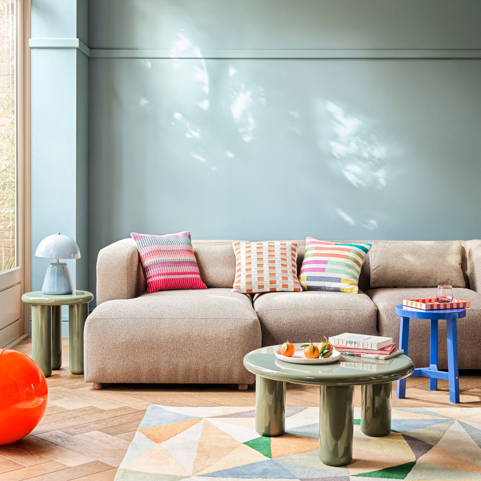 Habitat Geometric Patch Wool Cut Pile Rug in a sky blue lving room. There is an XL Calliban light in orange, beige sofa and green lacquered coffee table.