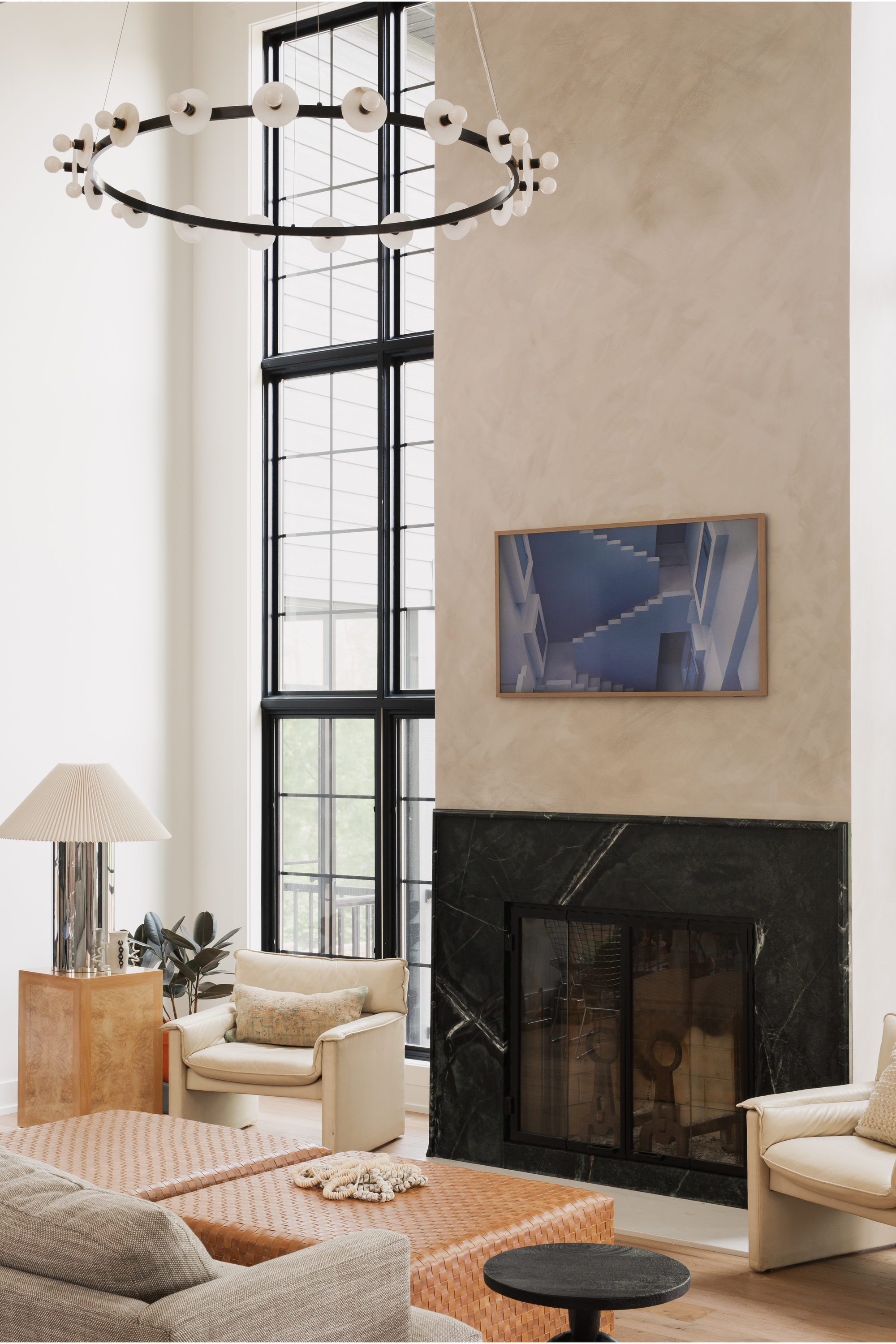 a lime washed living room with spotlight pendant, marble fireplace and table lamp