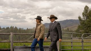 A press image of Luke Grimes as Kayce and Kevin Costner as John walking along a fence line in Yellowstone.