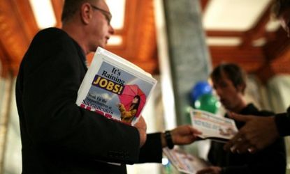 A worker passes out event materials at a San Francisco jobs fair last month: The unemployment rate dipped to 8.2 percent in March.