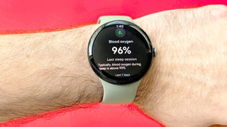 Close-up of the Pixel Watch 5 on a user's wrist against a bright red background