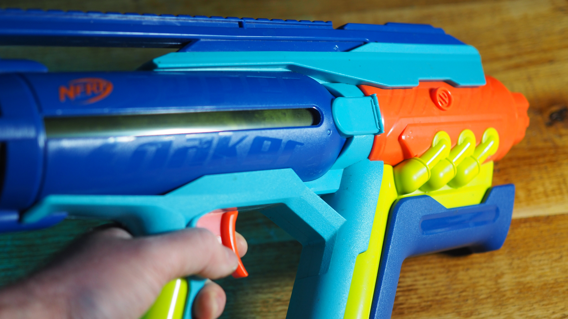 A hand holds a Super Soaker near a wooden surface