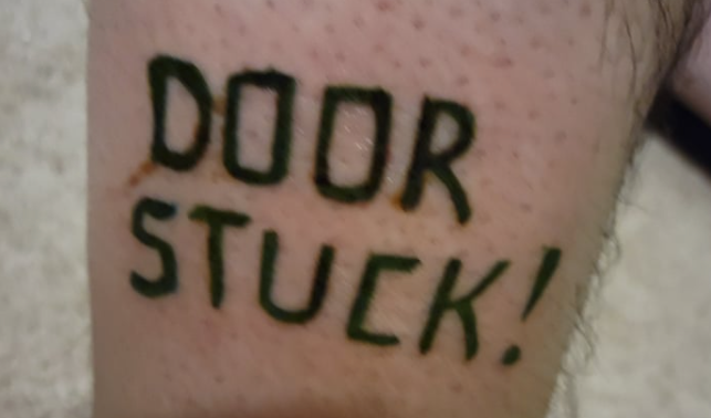 A tattoo of the words &#039;Door Stuck&#039; on a chap&#039;s leg.