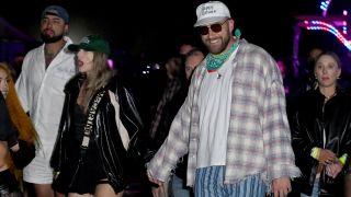 Taylor Swift and Travis Kelce holding hands while walking during Neon Carnival at Coachella on April 13.