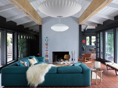 A living room with blue walls, a blue sofa, and a tall bookshelf