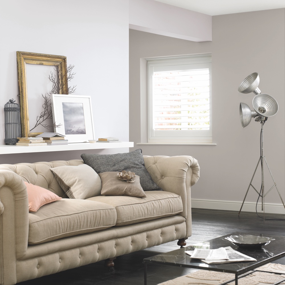 living area with white wall and wooden floor and sofa with cushion