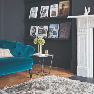 A living room painted in black with a marble fireplace and a shaggy rug in front of it