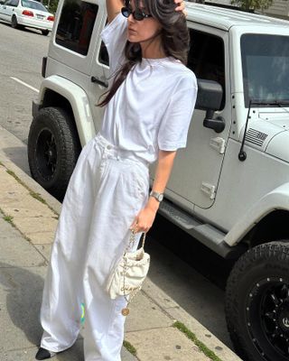 a woman wears a white T-shirt and baggy white jeans