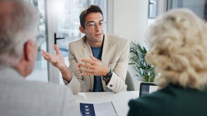 Over-the-shoulder shot of a senior couple talking with their financial adviser