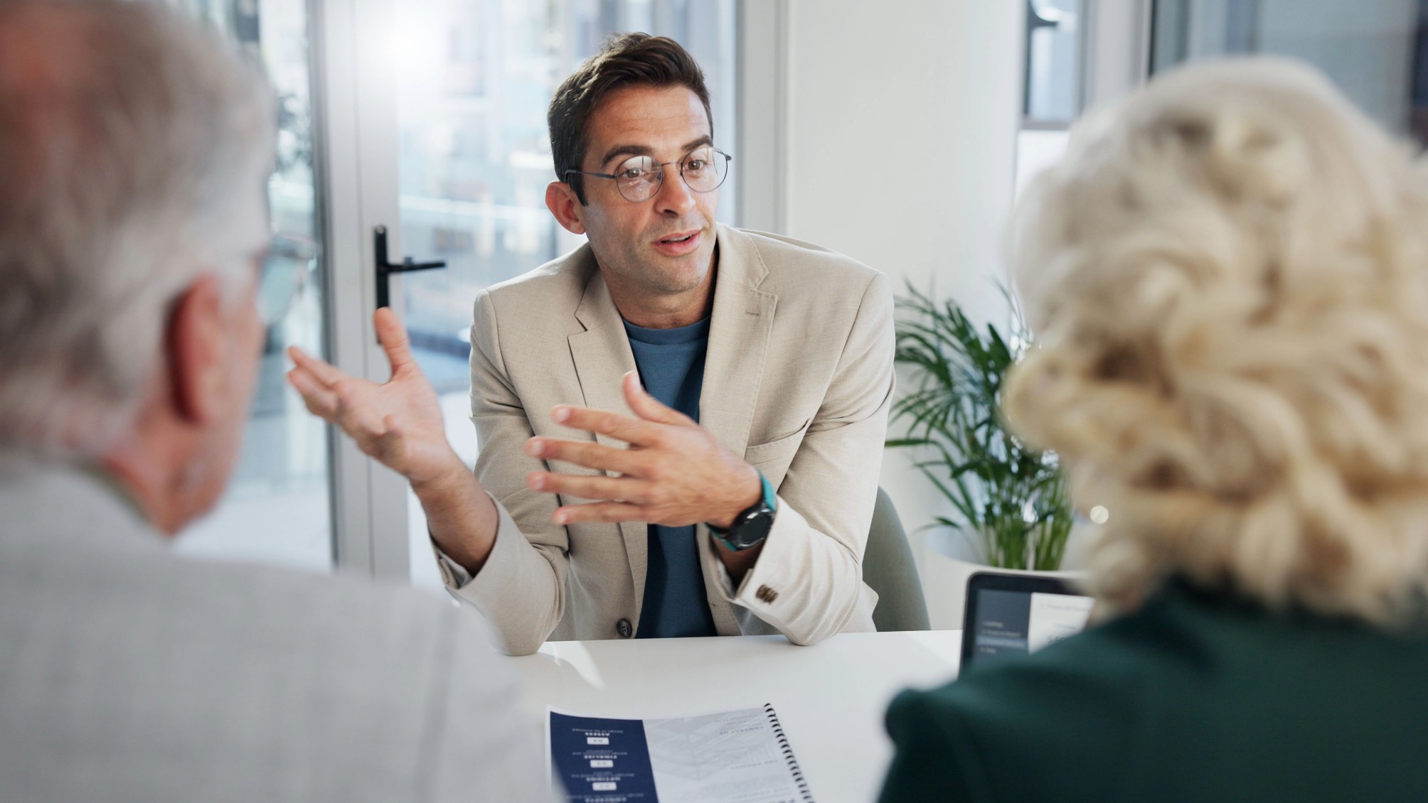 Over-the-shoulder shot of a senior couple talking with their financial adviser