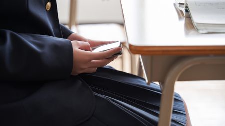 A student hides her cellphone underneath her desk in a classroom