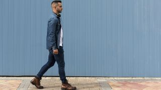 Man walking outside in front of a blue wall
