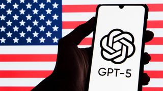 A GPT-5 logo is seen displayed on a smartphone with a blurred Flag of America in the background.