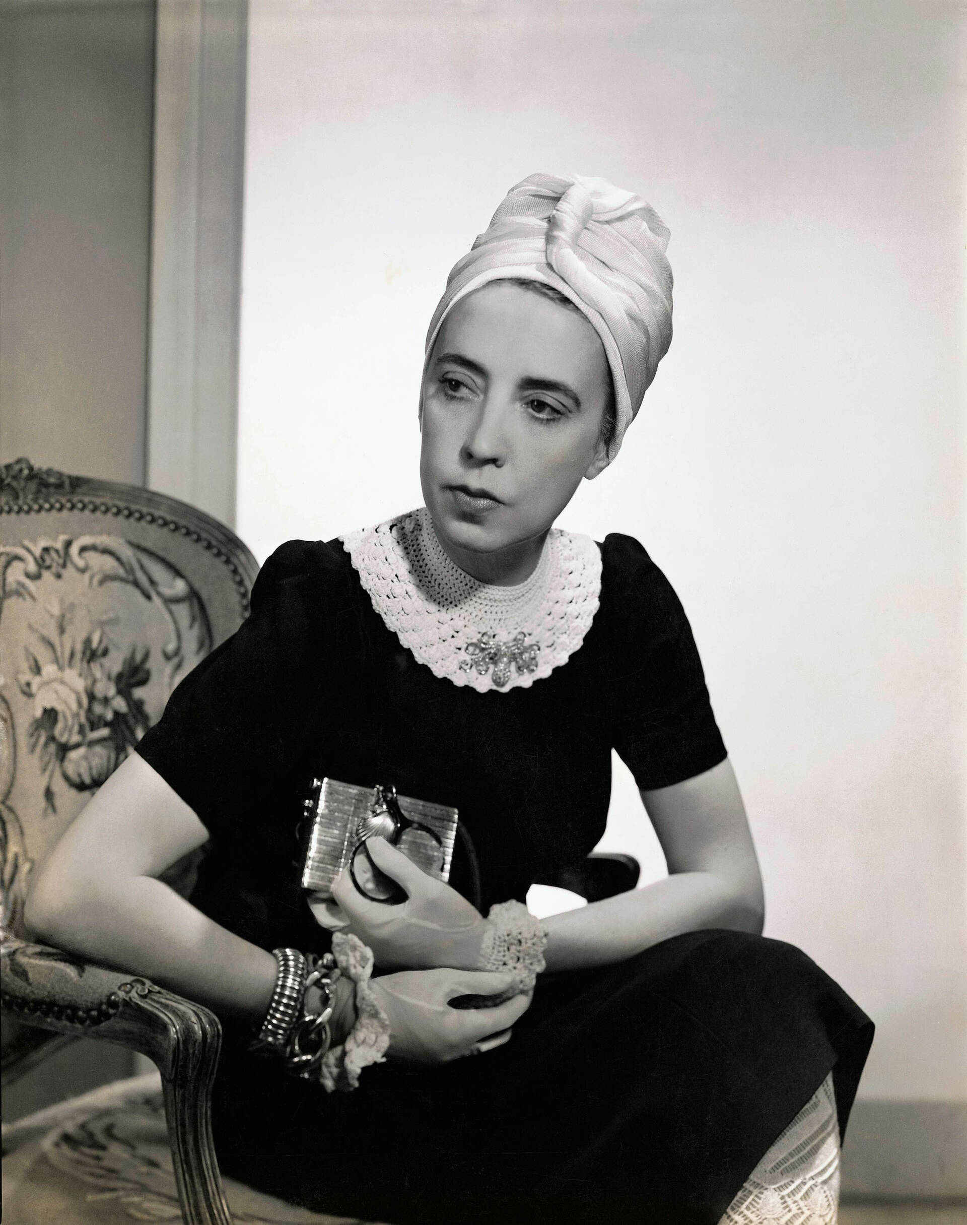 Designer Elsa Schiaparelli wearing black silk dress with crocheted collar of her own design and a turban, photograph by Fredrich Baker, Vogue, 1940