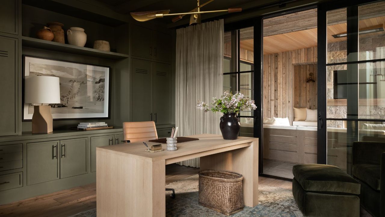 home office room with dark green walls and cabinets, light wooden desk, modern rustic decor