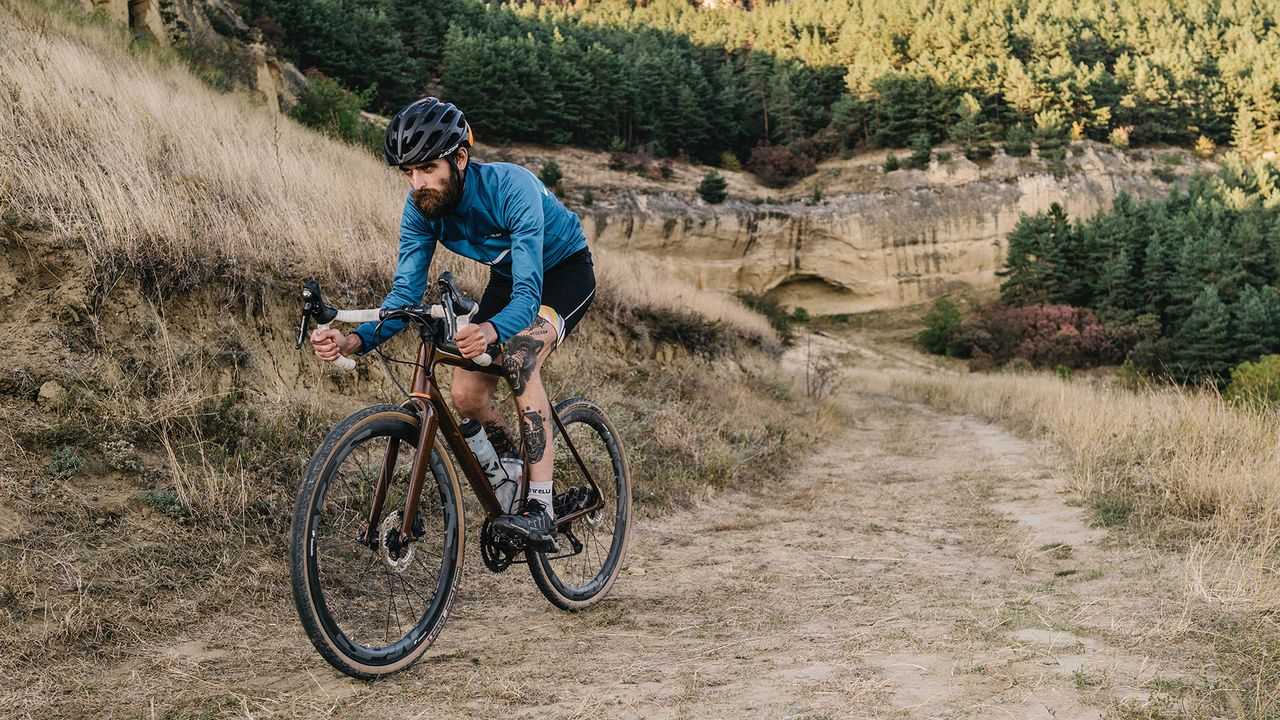 Man riding gravel bike in a hilly landscape