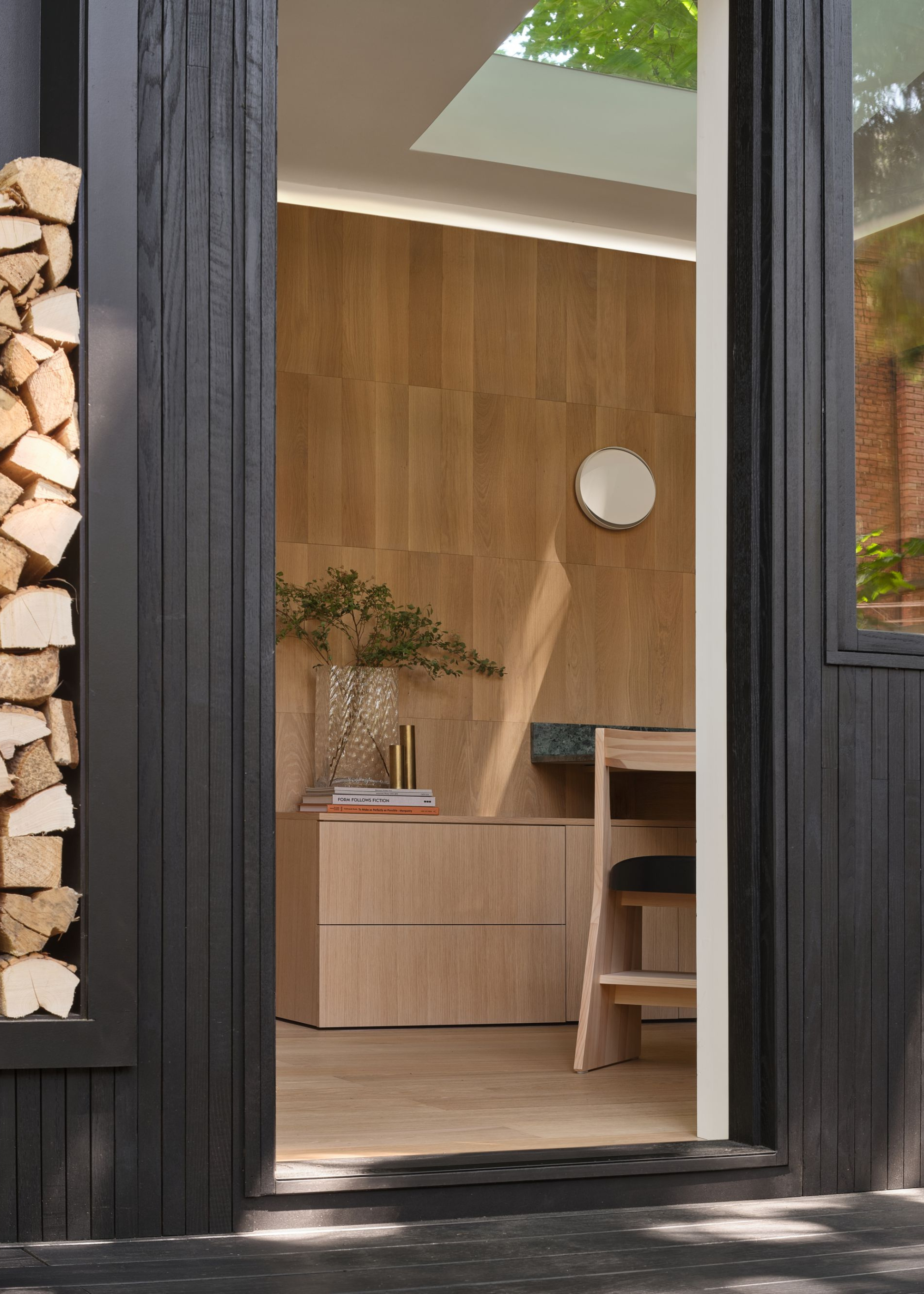 black wood garden shed with open door looking into the oak clad room with built-in desk and storage
