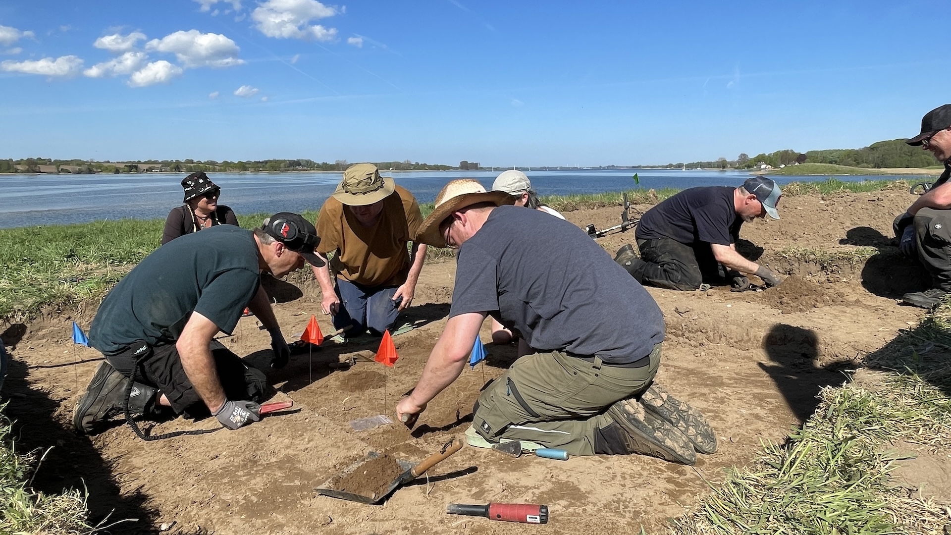 a group of archaeologists excavates a site by a lake