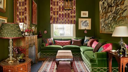 green color drenched living room with a green corner velvet sofa, patterned blind, cushions and rug for a loud luxury look