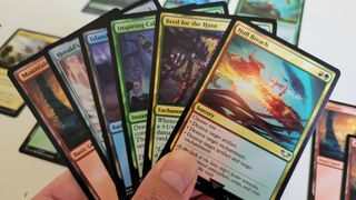 A series of Magic The Gathering cards being held in a hand