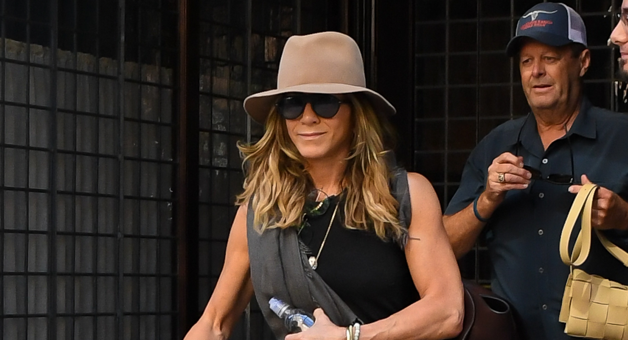Jennifer Aniston in New York wearing capri pants, flip flops, and a black tank top