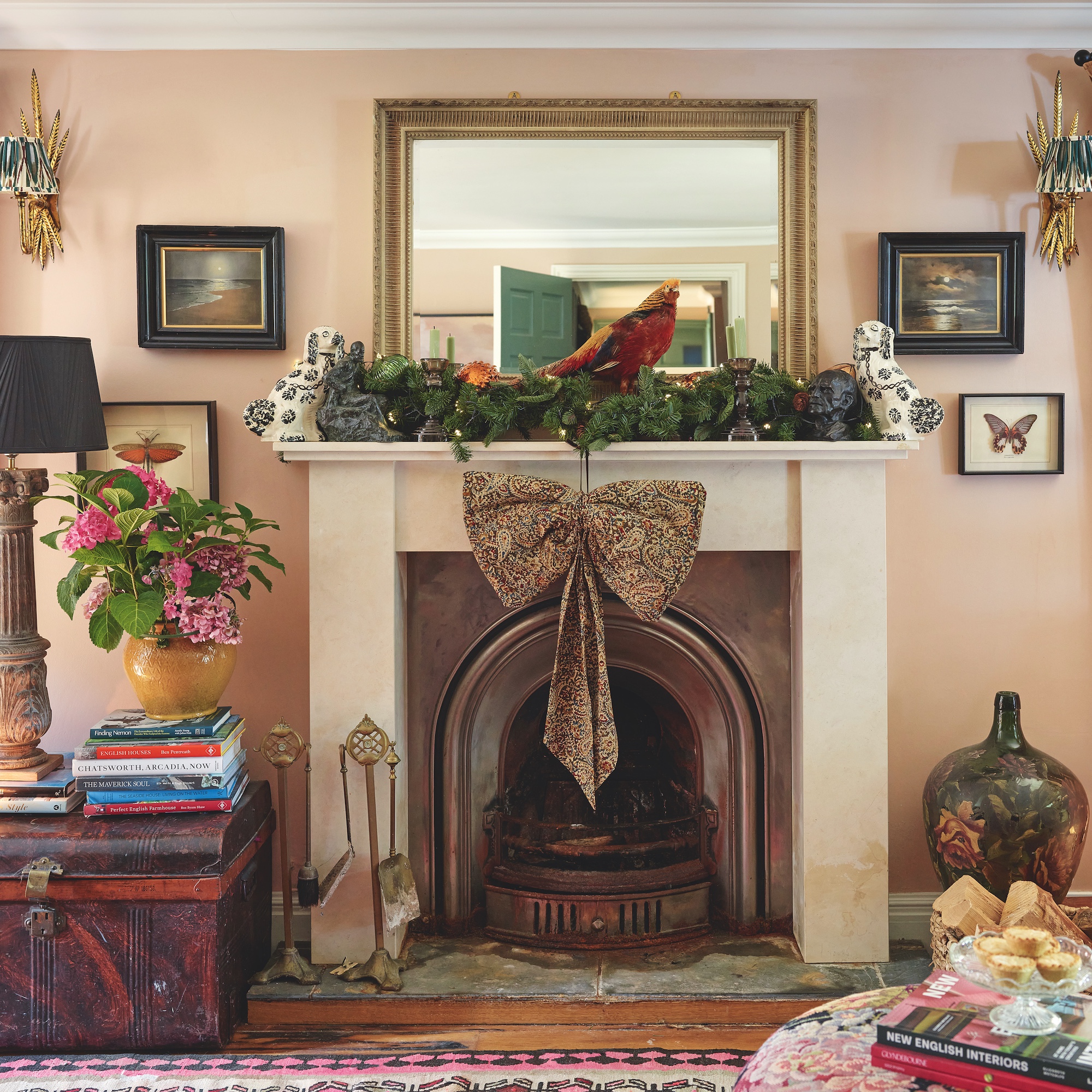 open fireplace decorated with bow and foliage in living room with pink walls and artwork on wall