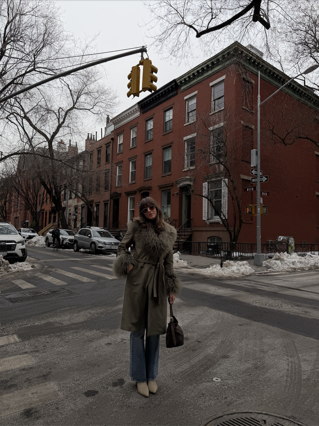 Kathryn Zahorak wearing fur-trimmed green coat, suede bag, jeans, sunglasses in new york city