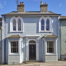 house exterior with blue wall and white window and black door and chimney