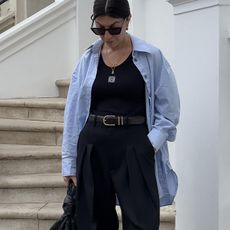 Woman wears blue shirt, black vest and black trousers