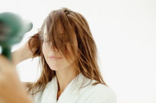 a close up of a woman using a hair dryer
