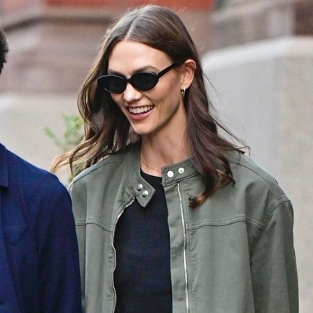 Karlie Kloss wears a green army jacket and black oval sunglasses