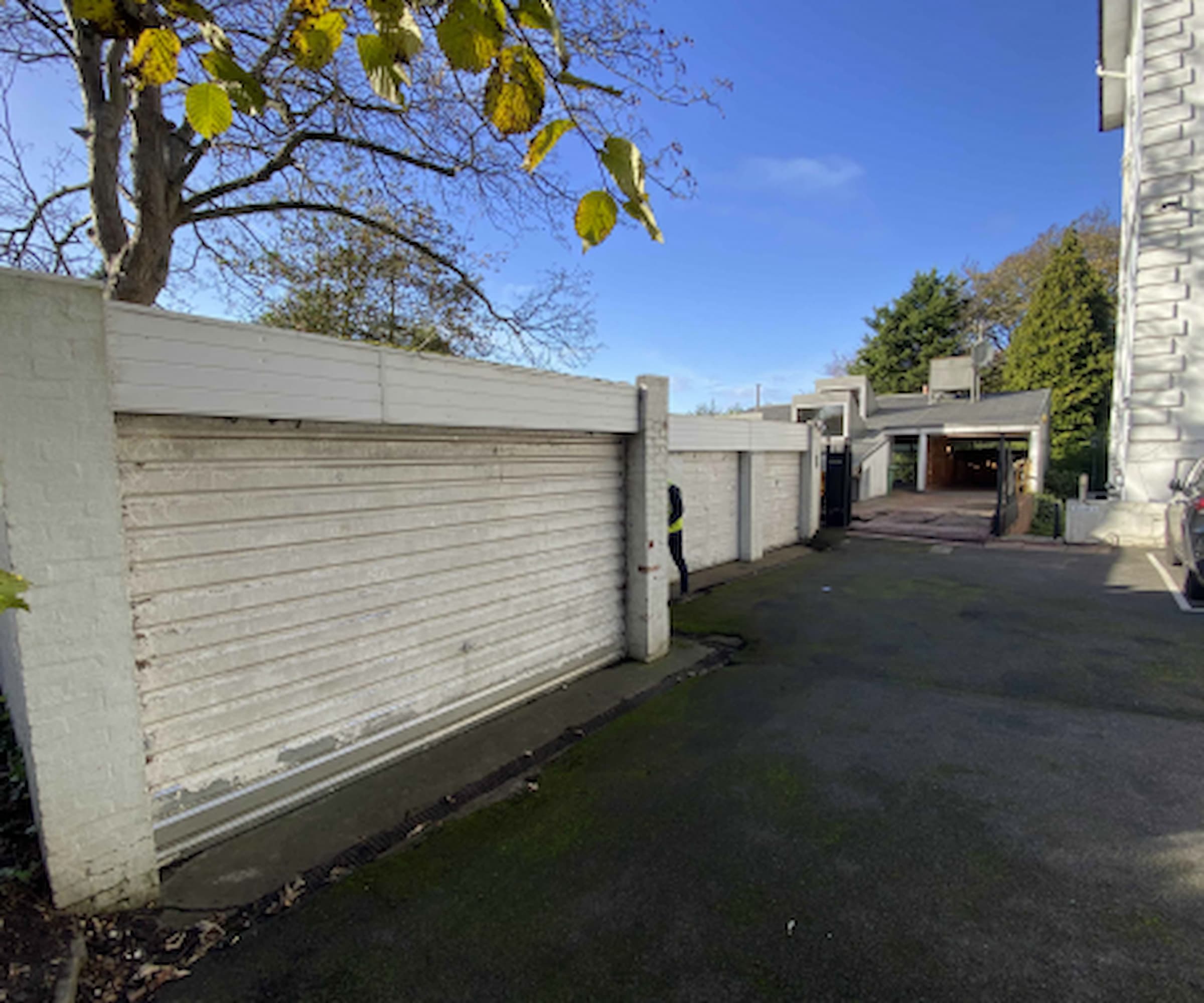 A white garage next to another white garage and a black paved driveway