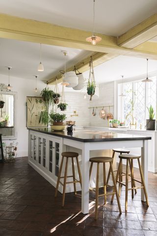 Kitchen with white cabinetry, large island with bar stools, white walls and tile floor