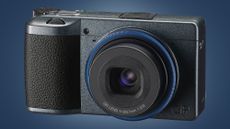 The RIcoh GR IIIx urban edition camera on a blue background