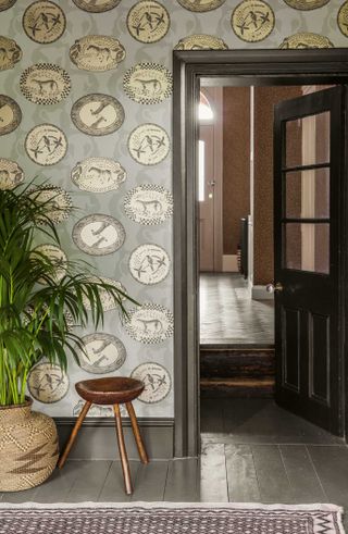 Cole & Son wallpaper in a hallway with wooden stool and palm tree