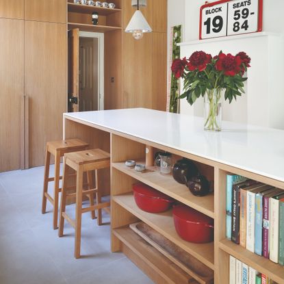 A light wood kitchen with an island in the middle holding cast iron casserole dishes